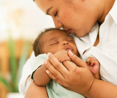 African American Woman Holding Newborn With the Fetal Development Stages