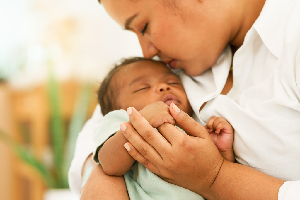 African American Woman Holding Newborn With the Fetal Development Stages