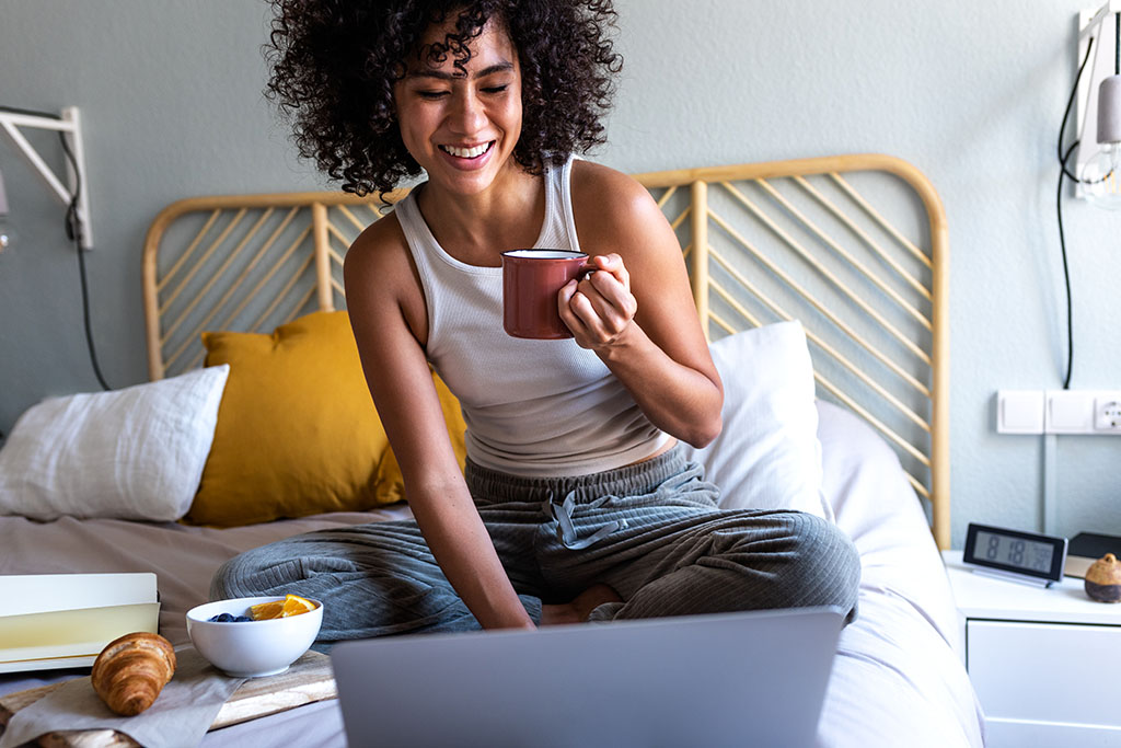 A Woman Smiling At Her Laptop Screen At Ease While Researching What Is A Laparoscopy