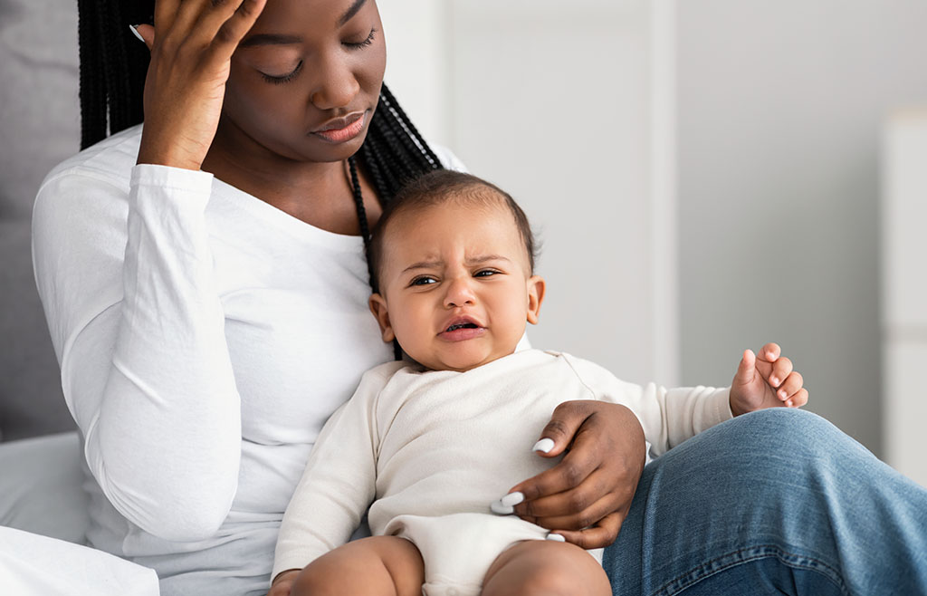 A New Mother With Her Crying Baby Sitting In Her Lap You're Postpartum, Now What?