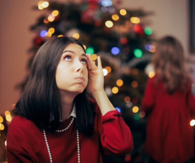 Woman Holding Her Head Stressed with Festive Lights in the Background Holiday Stress