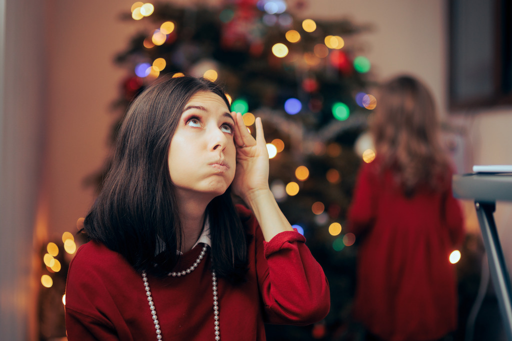 Woman Holding Her Head Stressed with Festive Lights in the Background Holiday Stress
