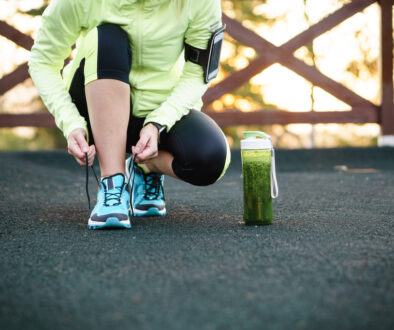Woman Lacing Shoes for a Workout with a Green Smoothie Beside Her Healthy Habits