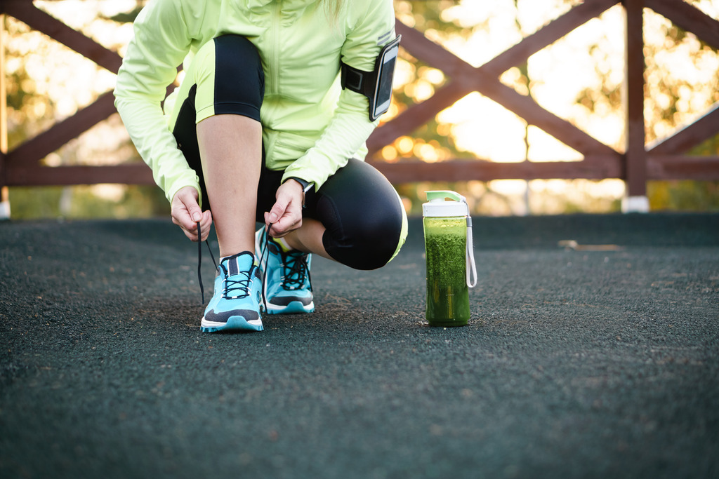 Woman Lacing Shoes for a Workout with a Green Smoothie Beside Her Healthy Habits